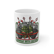White mug with a graphic design of grenades and a bow, and text 'Unwrap with Caution' on a white background.