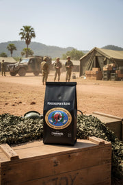 Coffee bag labeled 'Peacekeeper's Blend' on a wooden crate with military scene in the background